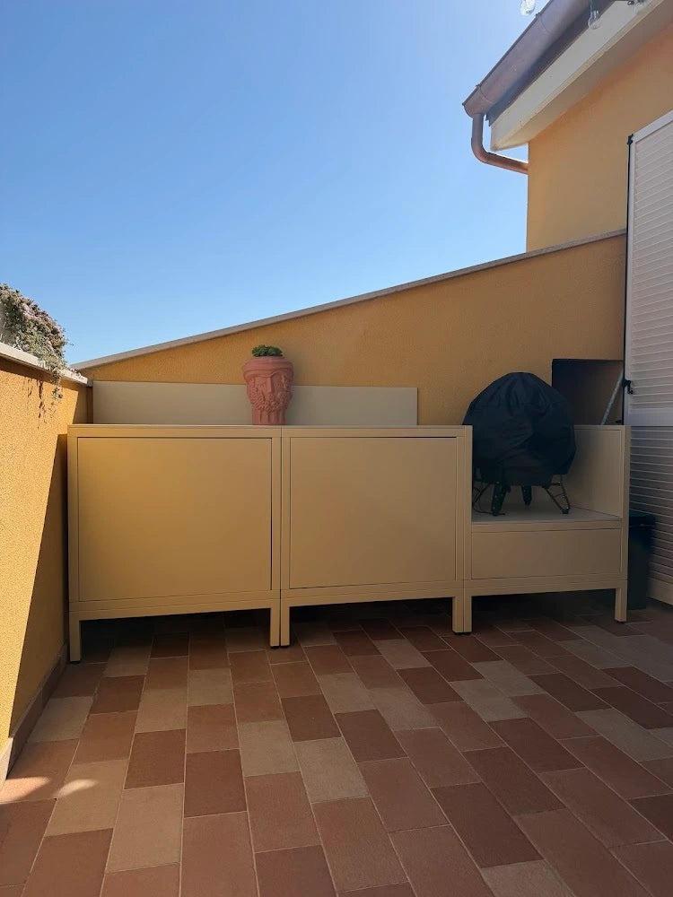 Cozinha exterior modular PILOTIS cor bege instalada em casa de um cliente, portas fechadas com espaço para barbecue integrado