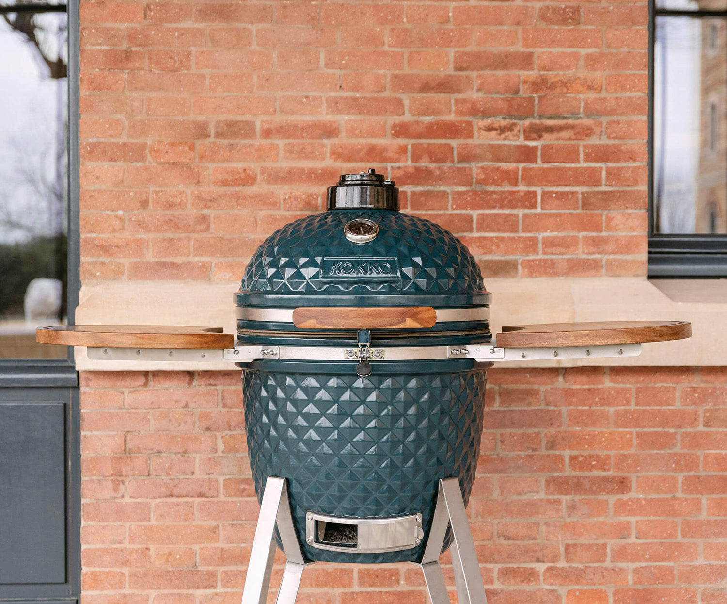 Kamado Kokko nova edição apresentado no seu carrinho, destacando o design, a cerâmica texturada e a integração num espaço exterior.