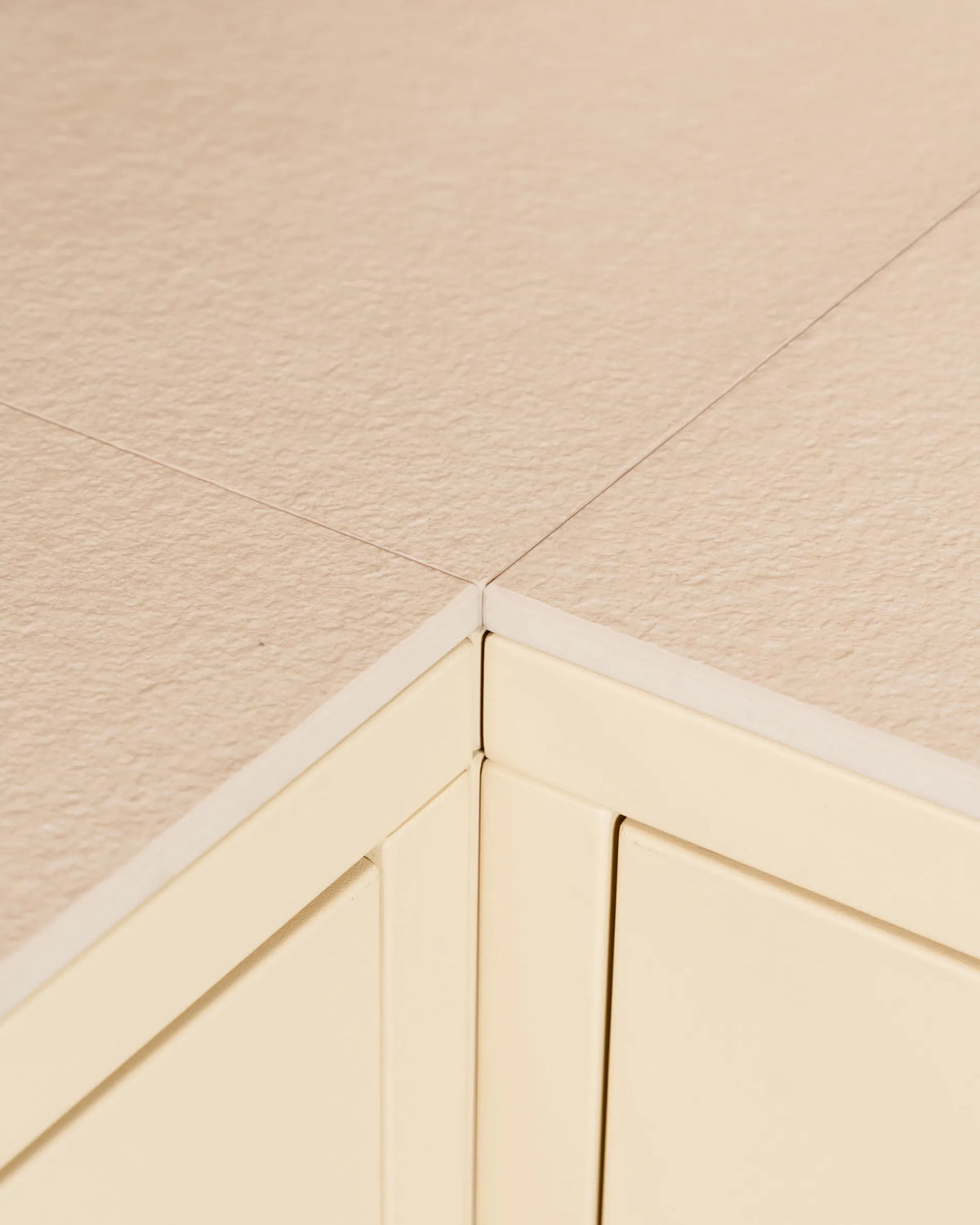 Detalhe do canto do tampo beige creme PILOTIS, com foco no recorte do caixote