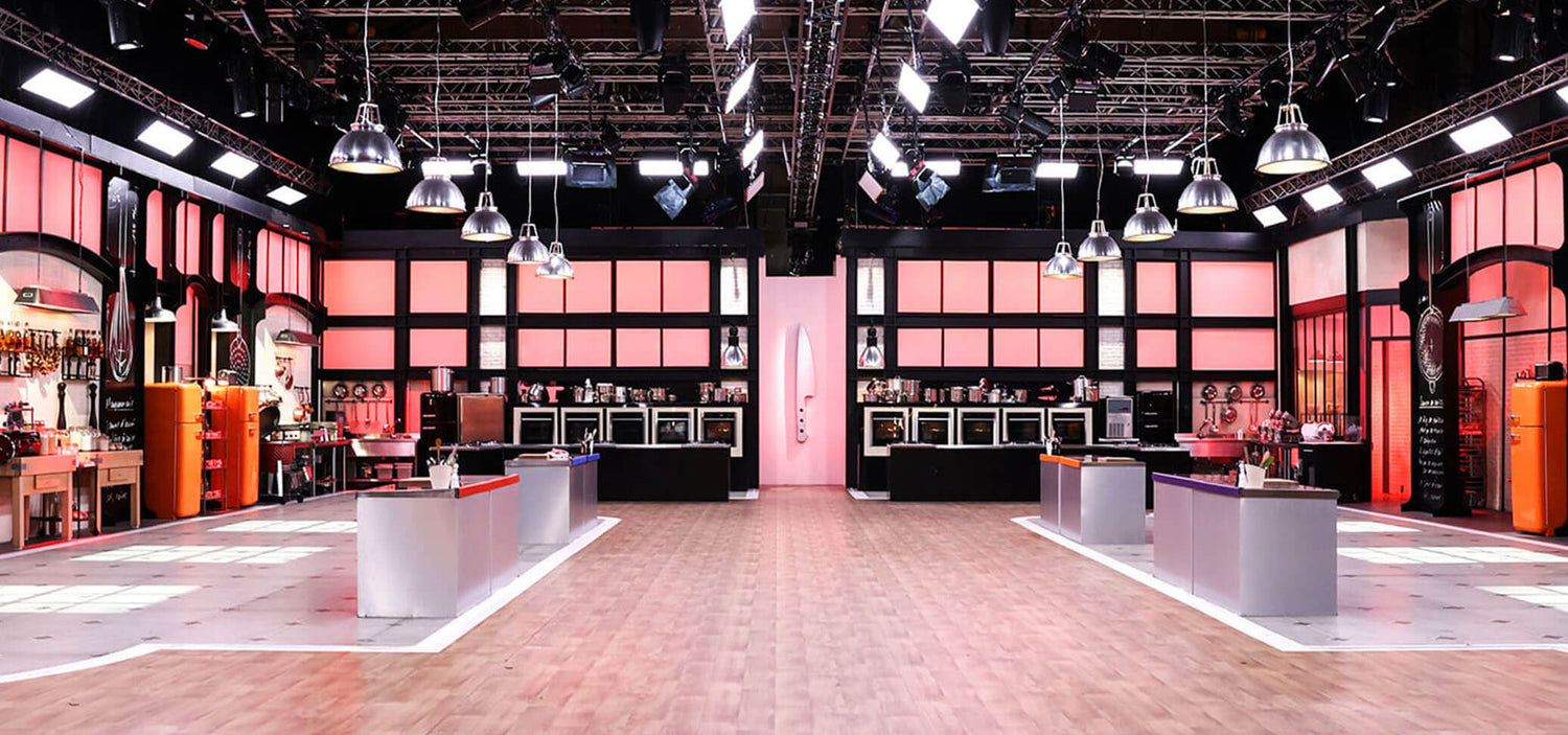 Plateau de gravação do programa Top Chef, com cozinhas profissionais, bancadas centrais e iluminação de estúdio.