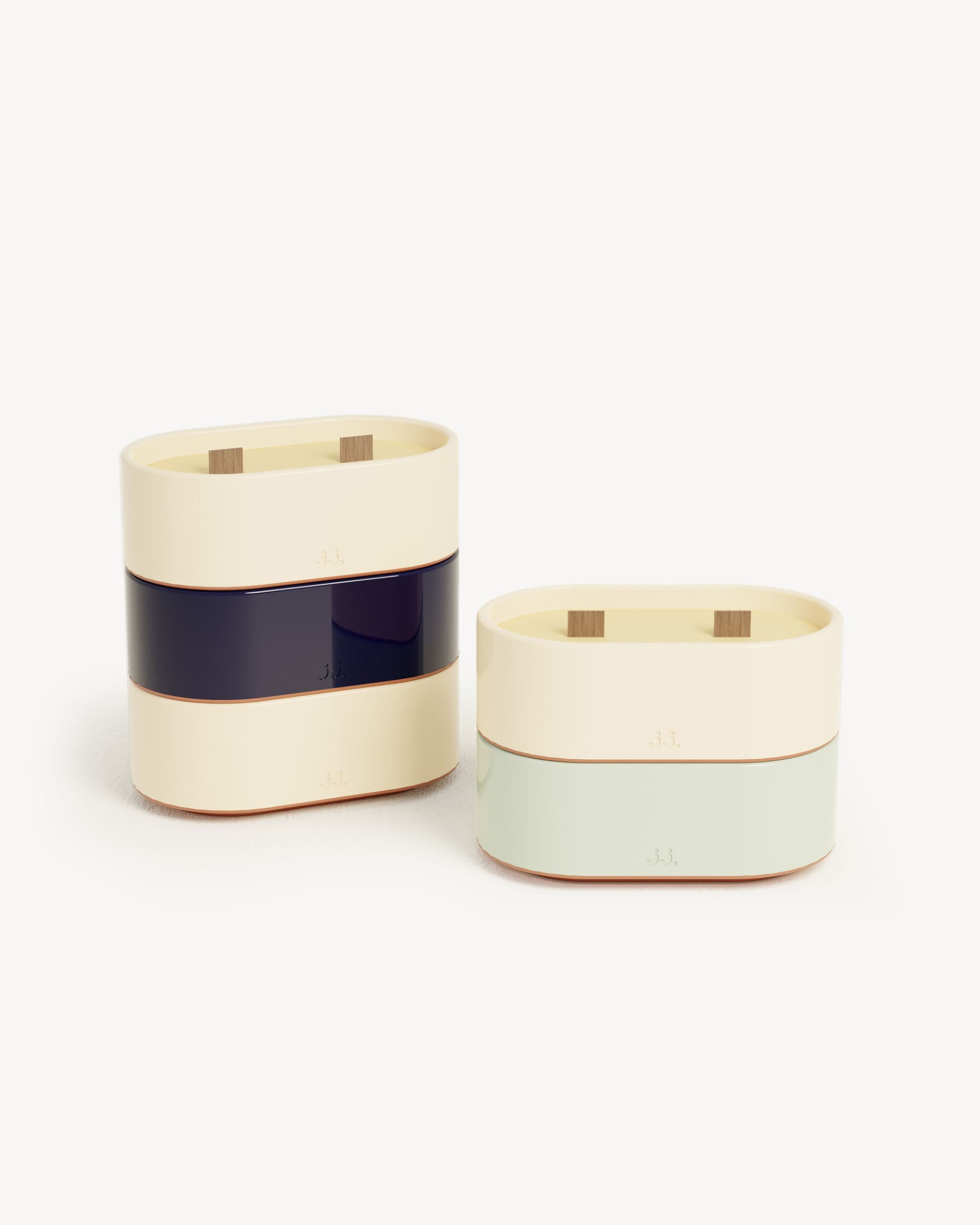 Bougie Totem S em cerâmica bicolor bege marfim e azul-marinho, perfumada com citronela e notas de limão e sal marinho, apresentada ao lado de uma versão verde-água com eucalipto.