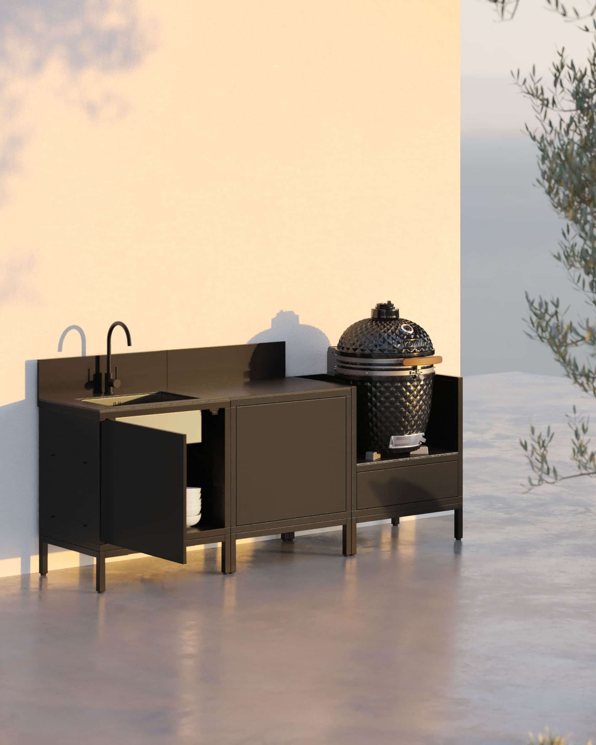 Cozinha pilotis de 3 módulos para kamado com lava-loiça integrado, móvel preto com bancada e painel traseiro a condizer, lava-loiça com torneira à esquerda, módulo central de arrumação fechado e kamado integrado no módulo lateral direito, estrutura com pés pretos, instalação no exterior.