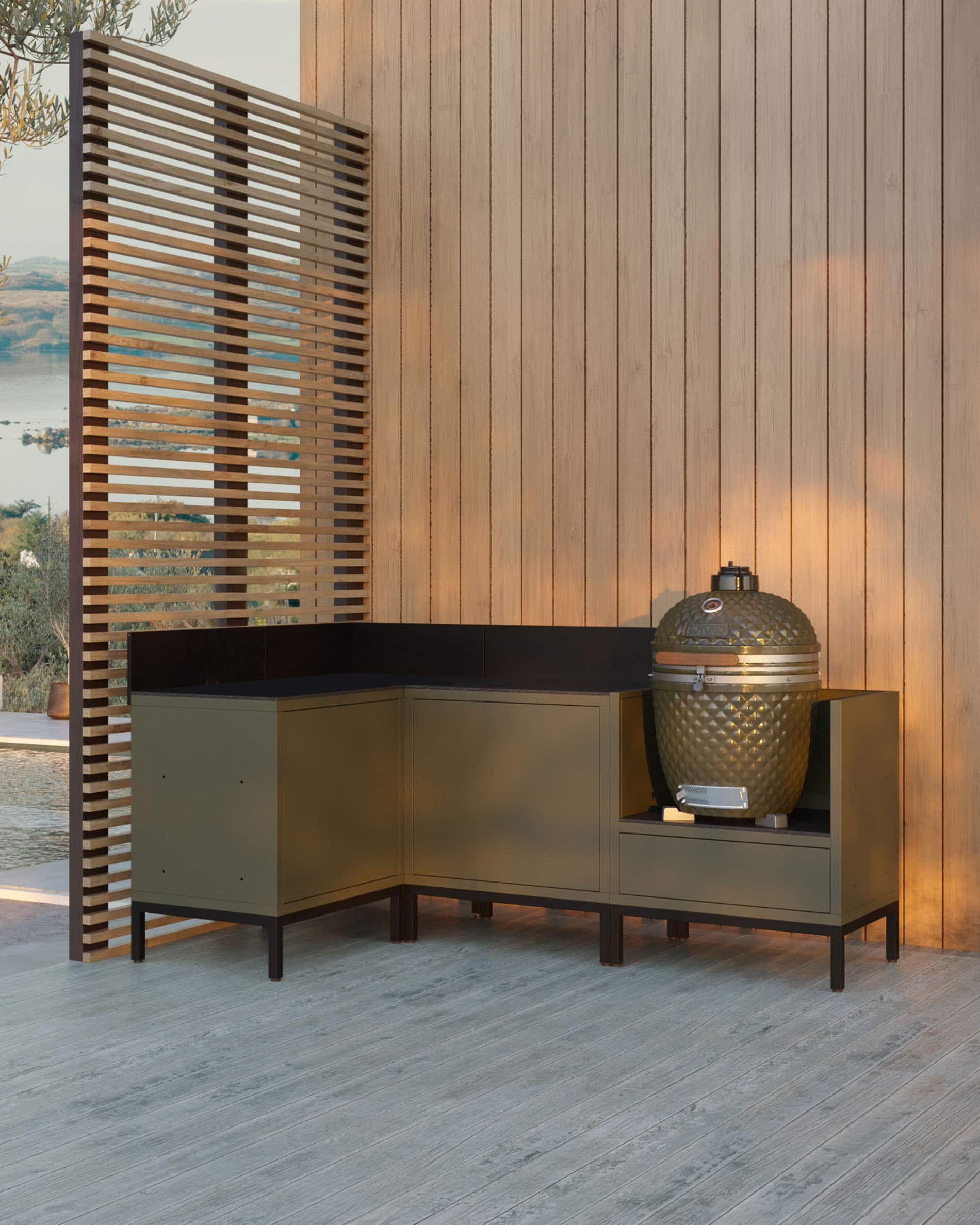 Módulo de cozinha pilotis de canto para kamado, conjunto de móveis em verde-azeitona com lava-loiça integrado, bancada escura e painel traseiro a condizer, kamado instalado no módulo lateral direito, estrutura com pés pretos.