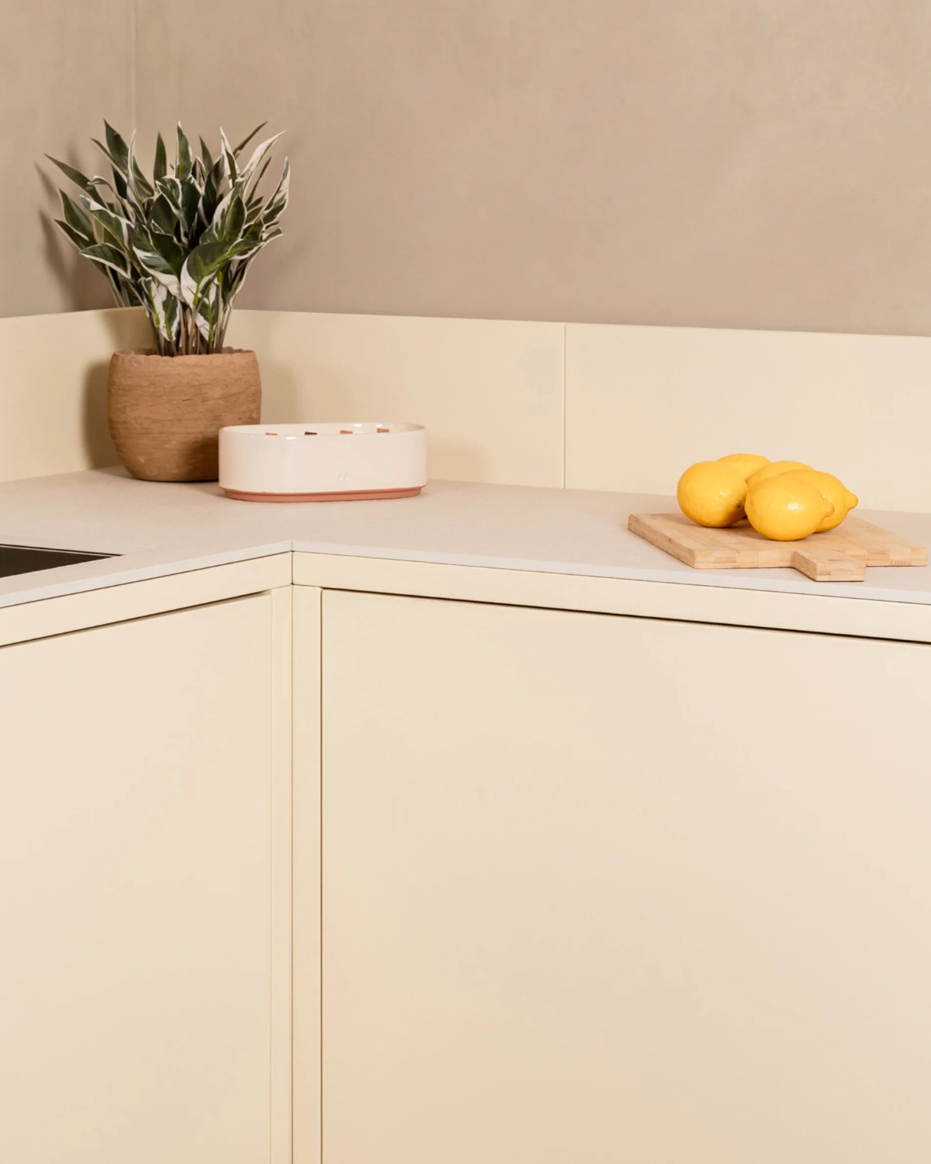 Detalhe do ângulo da cozinha exterior Kokko creme com bancada de trabalho e decoração vegetal