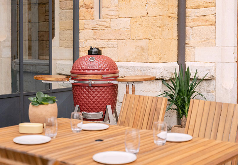 Área de cozedura de um kamado Kokko com grelha e acessórios em utilização.