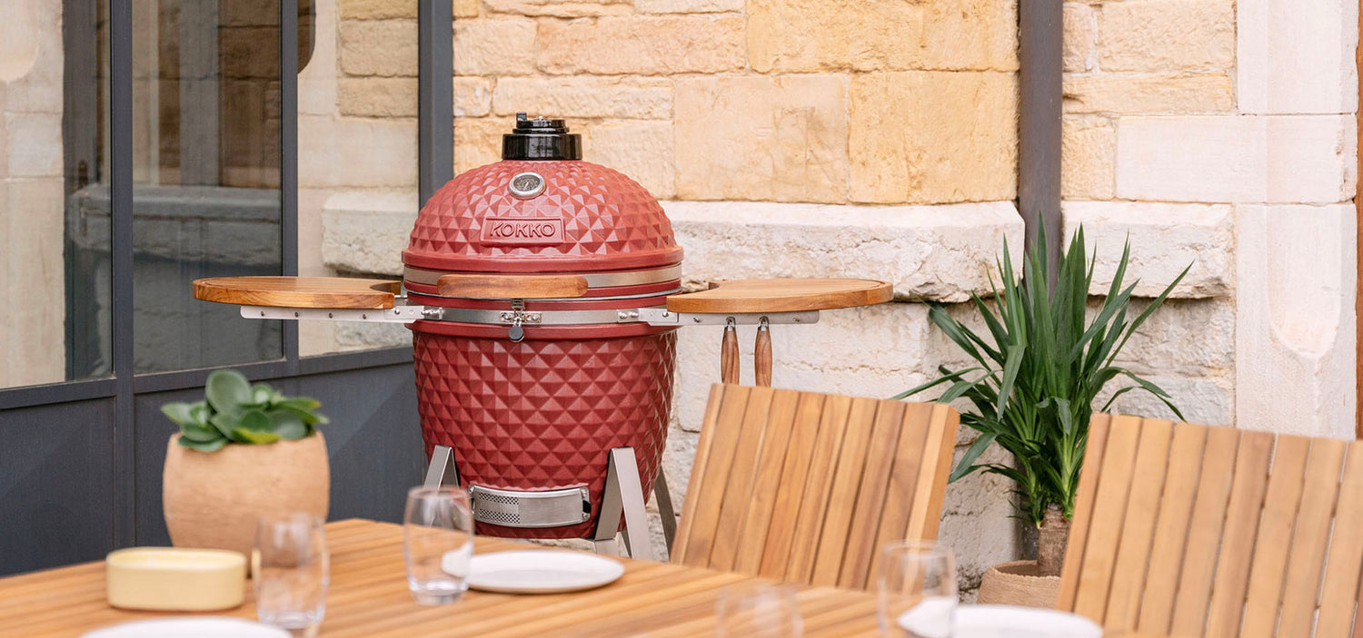 Kamado Kokko vermelho óxido instalado no exterior, ilustrando o universo e a história da marca.