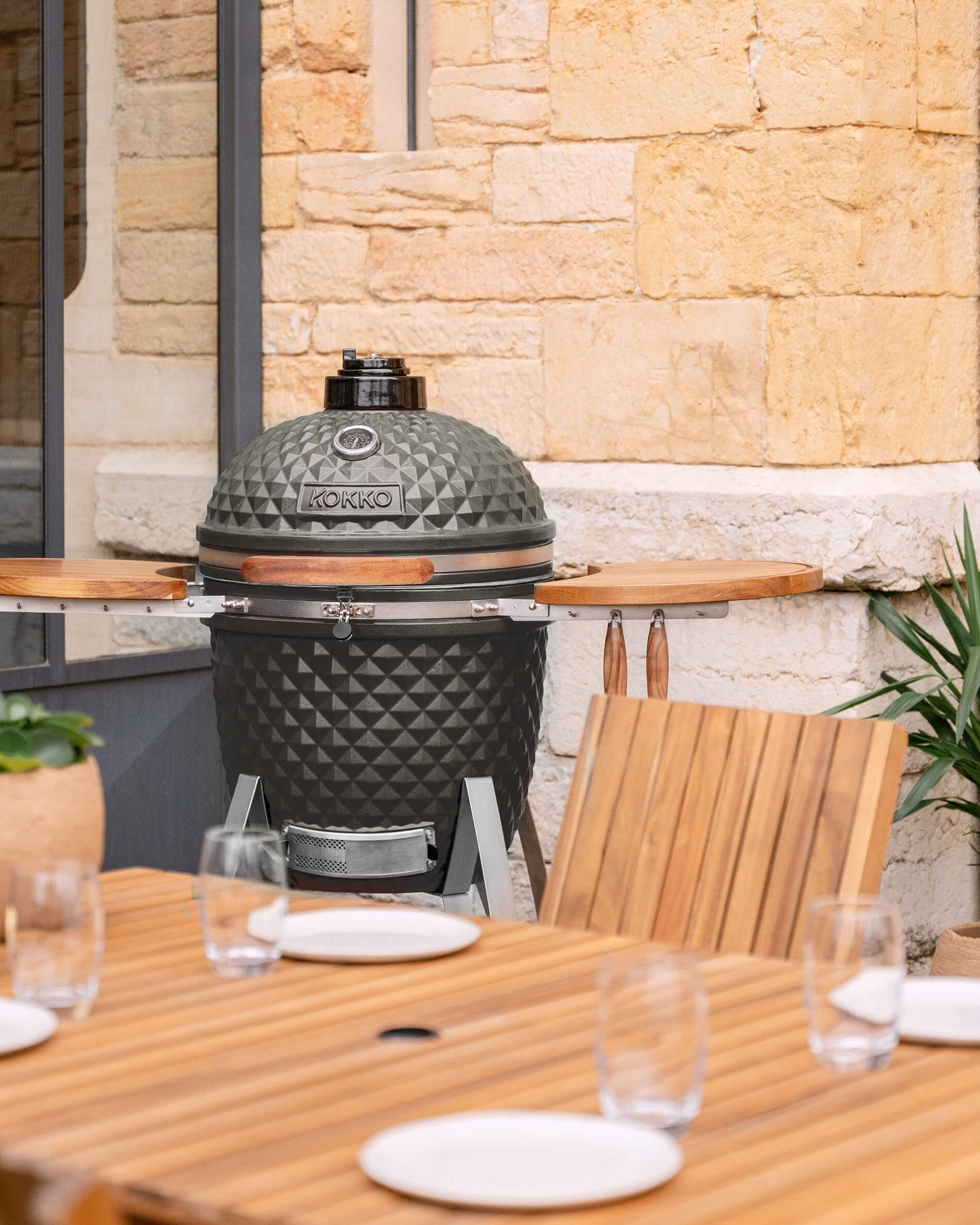 Kamado Kokko 22 polegadas em cerâmica verde-azeitona apresentado num terraço.