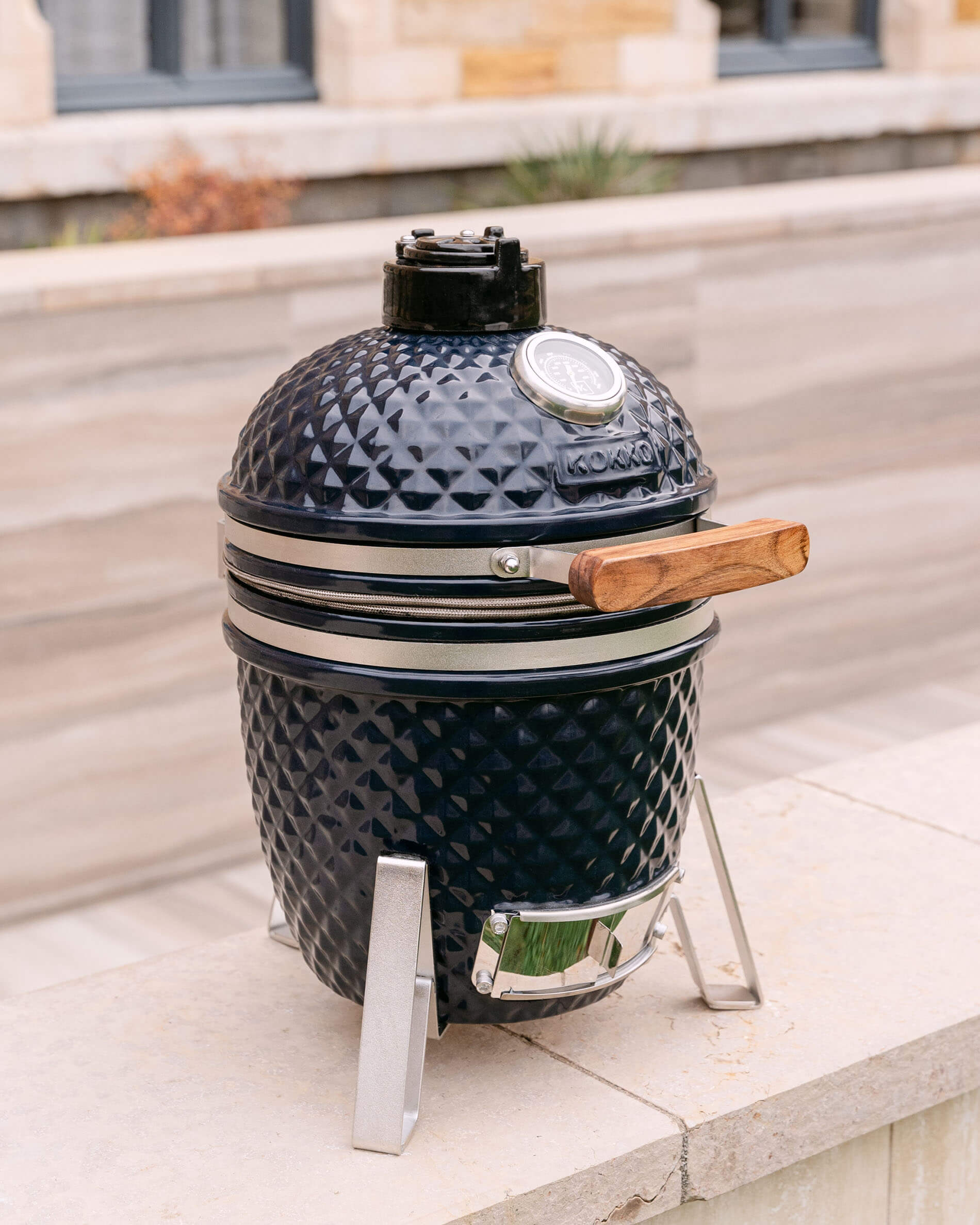Kamado Little Kokko 13 azul-marinho apresentado no seu suporte no exterior.