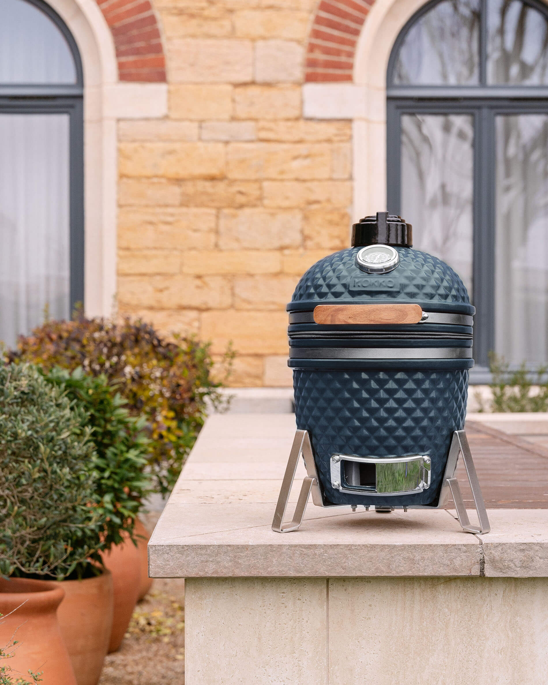 Kamado Little Kokko 13 em cerâmica azul oceano, instalado no exterior.