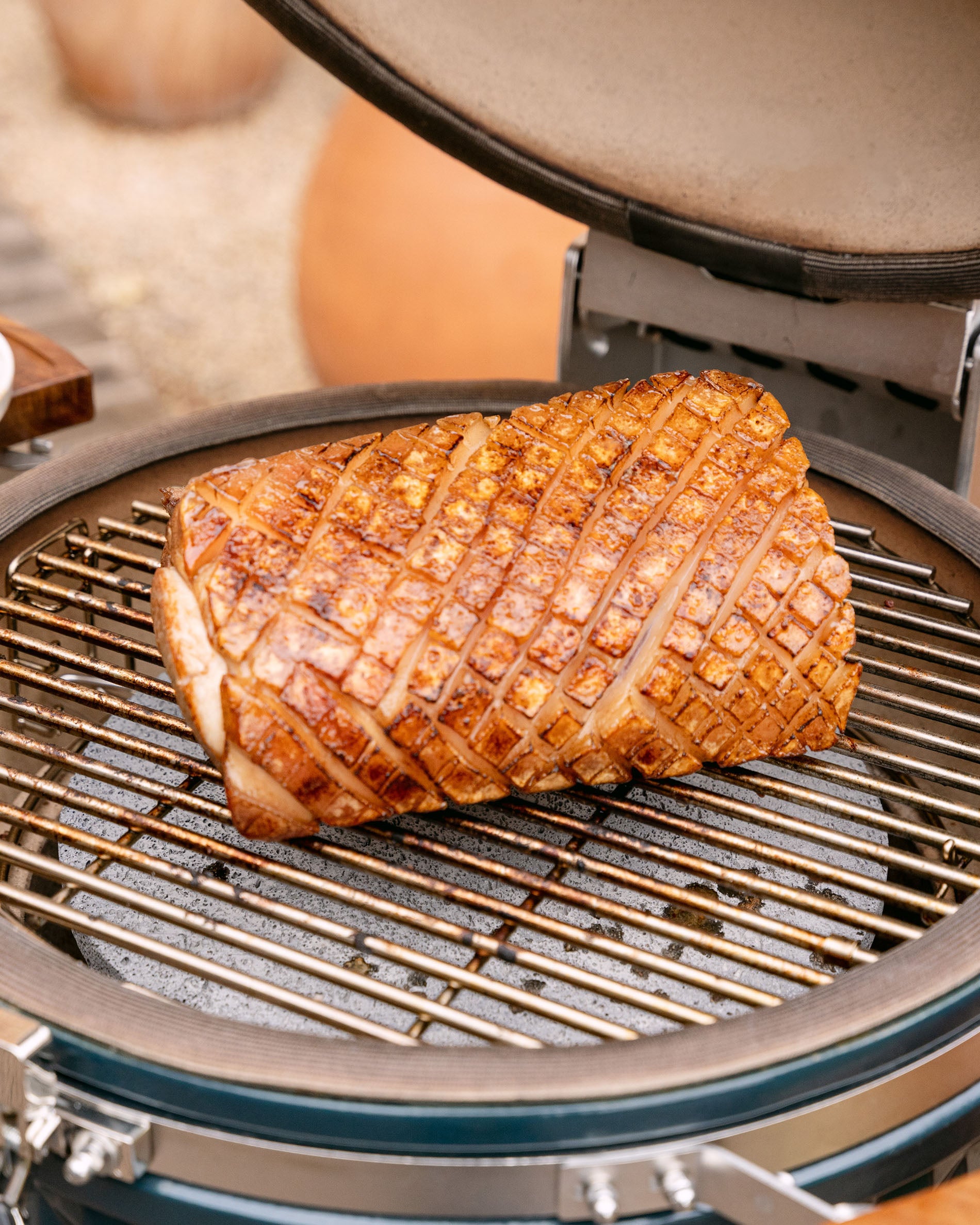 Assado de porco a cozinhar na grelha de um kamado Kokko, tampa aberta, com uma crosta dourada e uniforme.