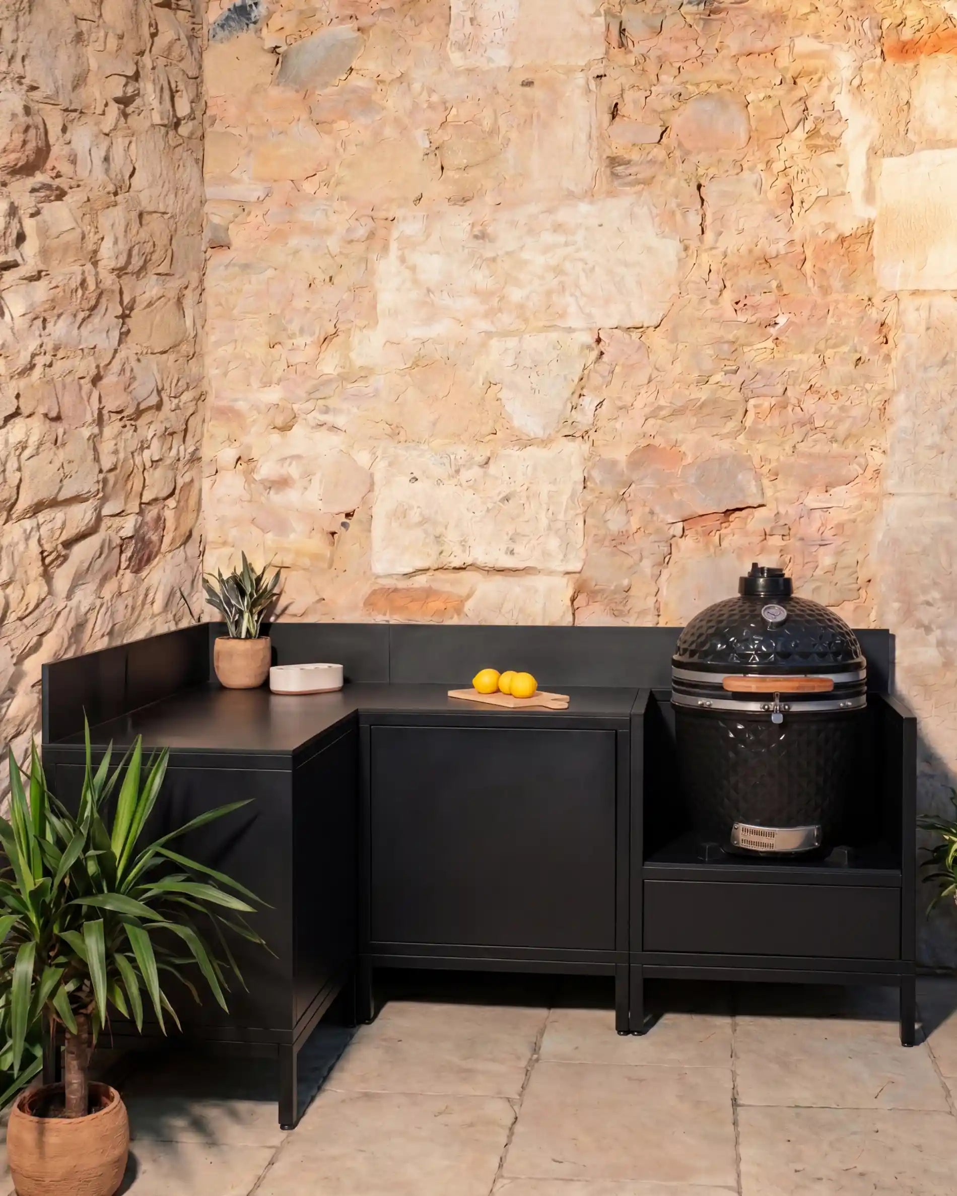 Cozinha exterior Kokko preta em ângulo com kamado e módulos de arrumação